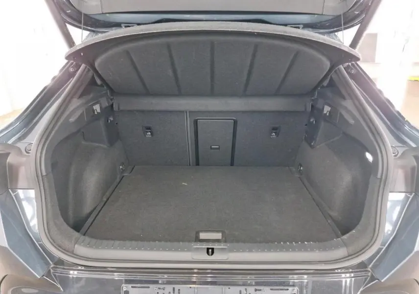 Coffre ouvert vu de l'arrière d'une CUPRA Formentor 2024 gris magnétique avec hayon électrique et intérieur noir.