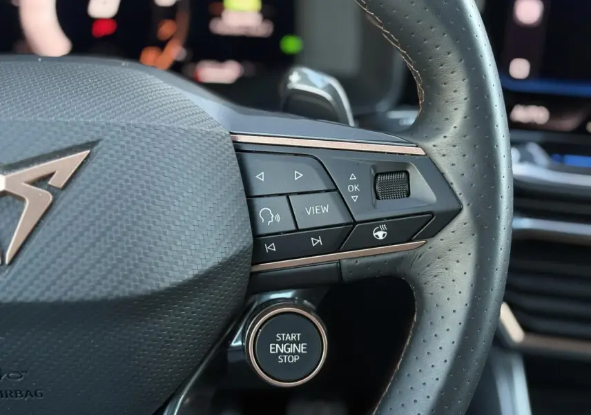 Gros plan sur le volant cuir perforé noir du CUPRA Formentor gris, avec commandes multifonctions et bouton Start Engine Stop.