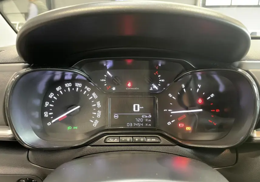 Vue rapprochée du tableau de bord numérique de la Citroën C3 blanche, affichant le compteur et les voyants allumés.