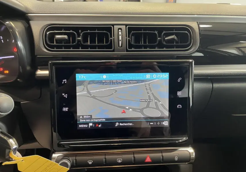 Vue rapprochée du tableau de bord noir brillant de la Citroën C3 2023 avec écran tactile de navigation allumé.