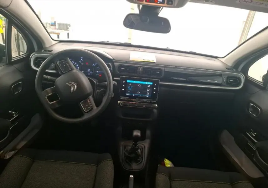 Vue intérieure avant du tableau de bord et volant noir de la Citroën C3 blanche avec écran tactile central allumé.