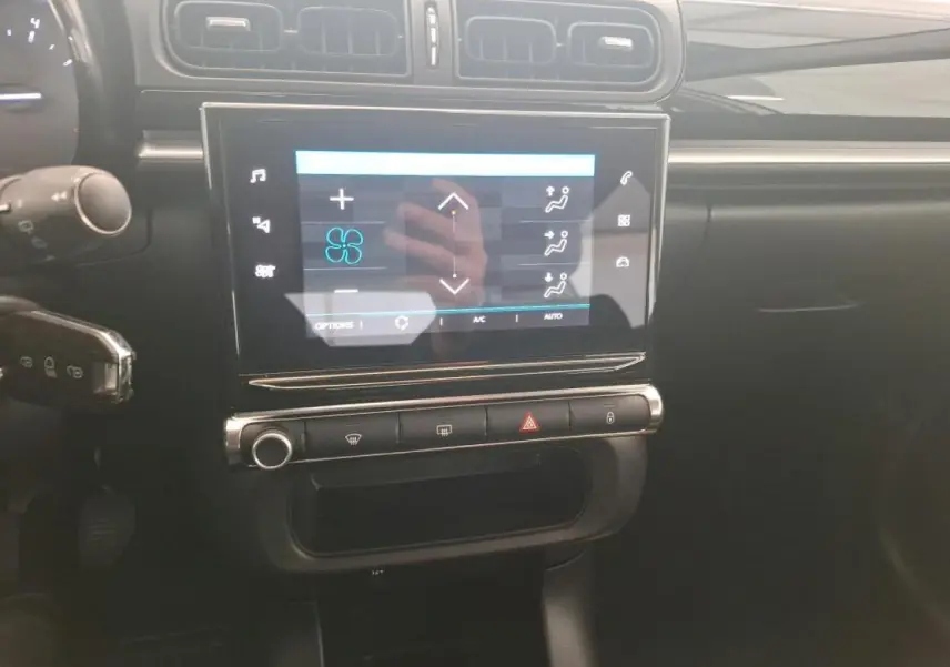 Vue rapprochée de la console centrale noire brillante de la Citroën C3 avec écran tactile affichant la climatisation.