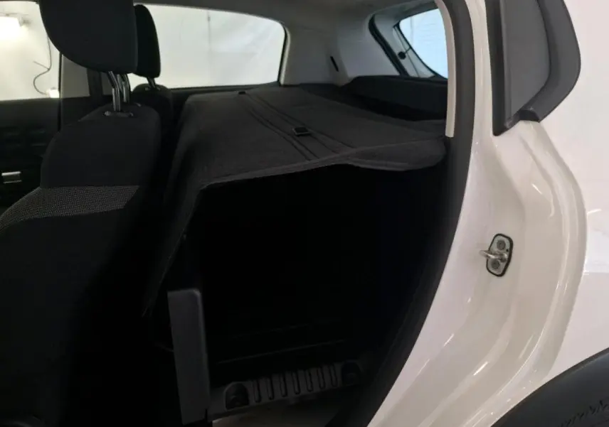 Vue intérieure côté droit du coffre d'une Citroën C3 blanche avec banquette arrière rabattue et cache-bagages déployé.