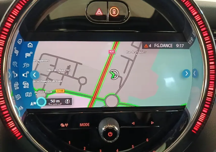 Gros plan sur l'écran central tactile du tableau de bord de la MINI noire, affichant la navigation avec éclairage rouge circulaire.