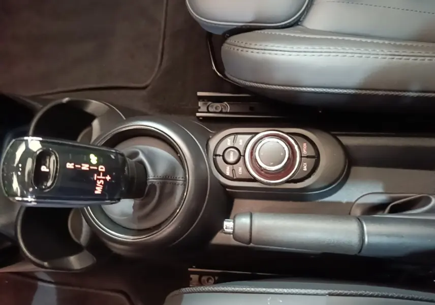 Vue rapprochée du levier de vitesses automatique et molette de commande centrale de la MINI Cooper noire, intérieur cuir gris.