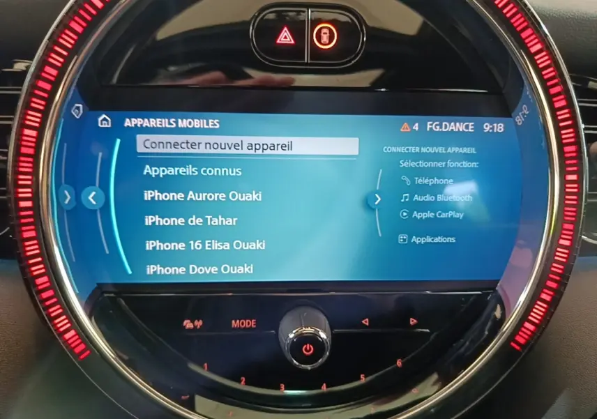 Écran tactile central circulaire de MINI Cooper noir 2023 avec interface connectivité mobile et anneau lumineux rouge.