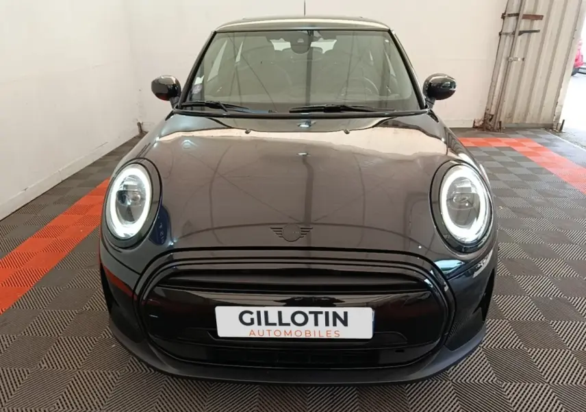Vue frontale d'une MINI Cooper Edition Premium Plus noire avec phares LED circulaires allumés en intérieur.
