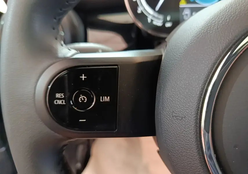 Gros plan sur la commande de régulateur de vitesse côté gauche du volant cuir noir d'une MINI Cooper 2023.