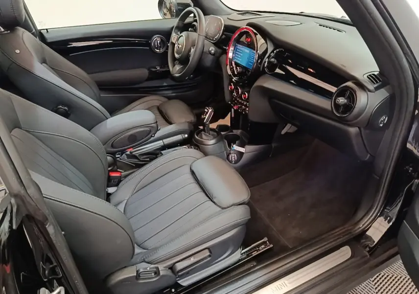 Vue intérieure côté conducteur de la MINI Cooper Edition Premium Plus noire, avec tableau de bord et sièges en cuir noirs.