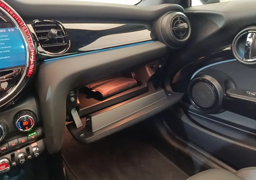 Vue intérieure côté passager de la MINI Cooper Edition Premium Plus 2023 noire, avec boîte à gants ouverte et tableau de bord noir brillant.
