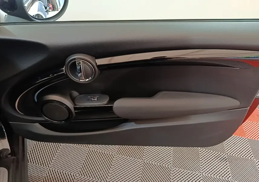 Vue intérieure côté gauche de la porte noire d'une MINI Cooper Edition Premium Plus 2023 avec commande de vitre et haut-parleur intégré.