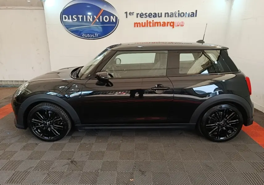 Profil droit d'une MINI Cooper Edition Premium Plus noire 3 portes avec jantes noires brillantes en intérieur showroom.