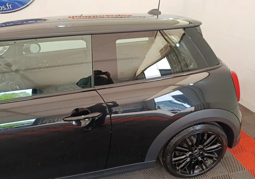 Vue latérale droite d'une MINI Cooper Edition Premium Plus noire avec jantes alliage noires brillantes et toit noir.
