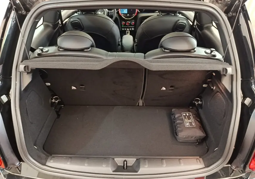 Vue arrière du coffre ouvert d'une MINI Cooper Edition Premium Plus noire, montrant l'intérieur et la banquette arrière.