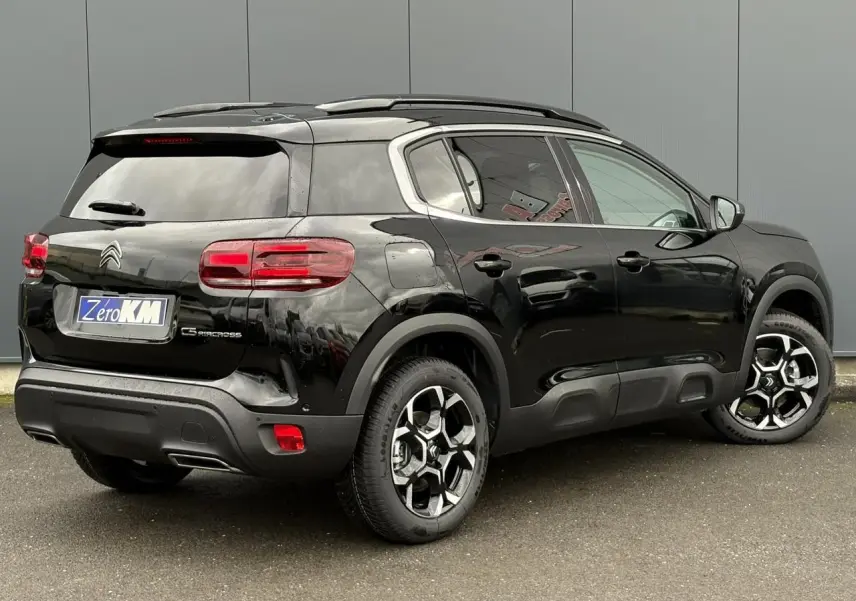 Vue 3/4 arrière droite du Citroën C5 Aircross noir Perla avec jantes alliage bi-ton et barres de toit noires.
