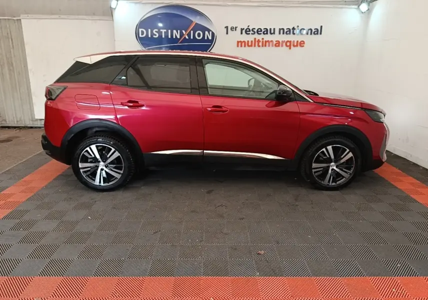 Vue de profil côté droit d’un Peugeot 3008 PureTech 130 rouge avec jantes alliage et toit noir dans un showroom.