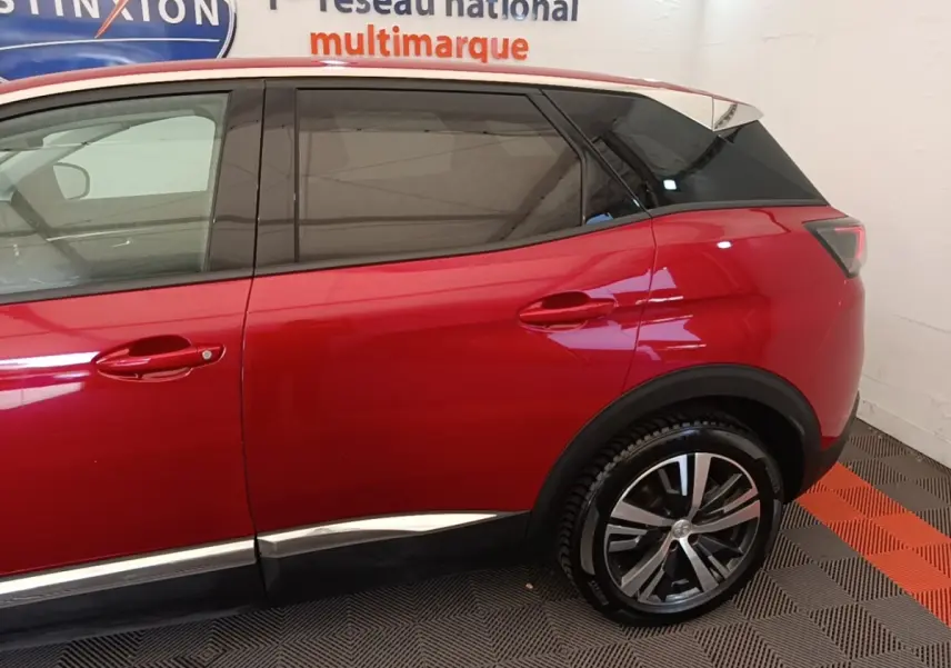 Vue latérale droite d’un Peugeot 3008 rouge avec jantes alliage et vitres teintées, intérieur showroom.