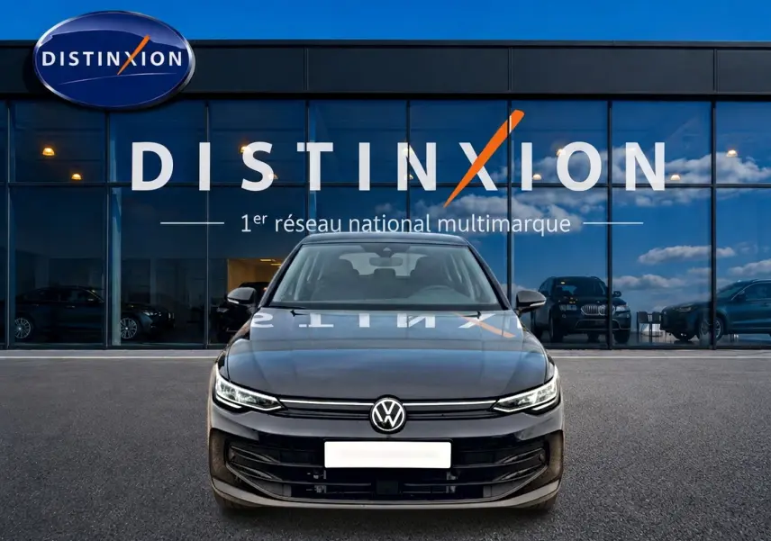 Vue frontale d'une Volkswagen Golf noire 2026 garée devant une vitrine avec logo Distinxion.