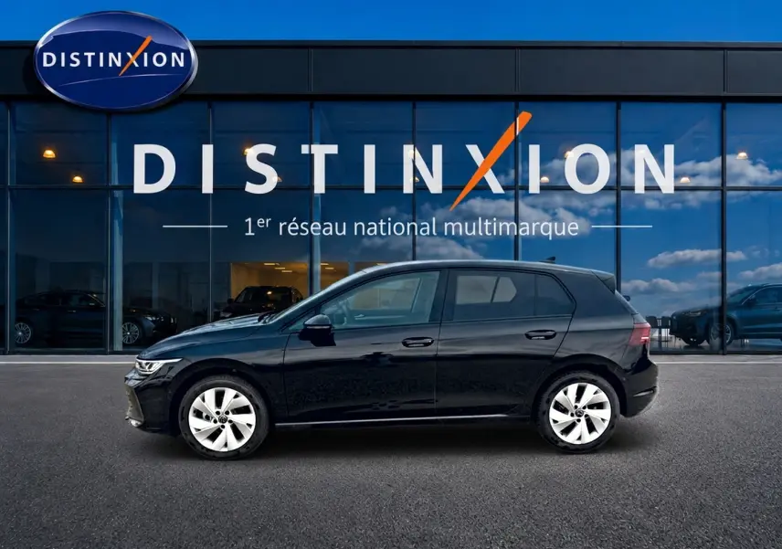 Profil droit d'une Volkswagen Golf noire 2026 garée devant une vitrine avec logo Distinxion.
