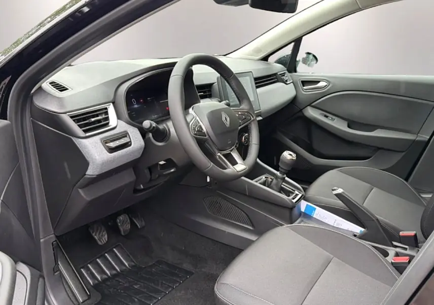 Vue intérieure côté conducteur de la Renault Clio V noire, montrant le volant multifonction et la boîte manuelle.