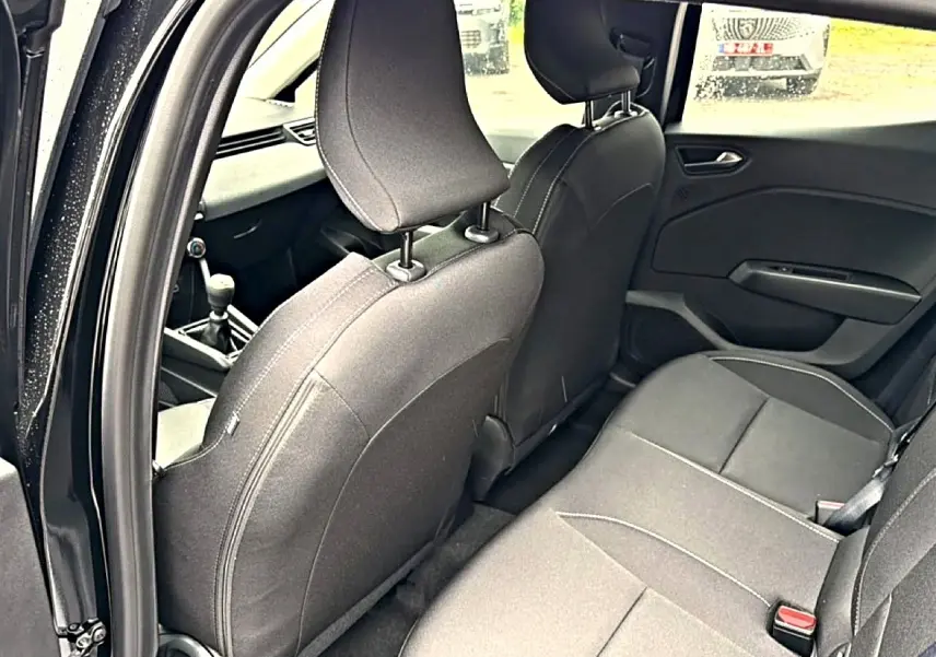 Vue intérieure arrière côté gauche de la Renault Clio V noire, montrant les sièges et la console centrale avec levier de vitesse.
