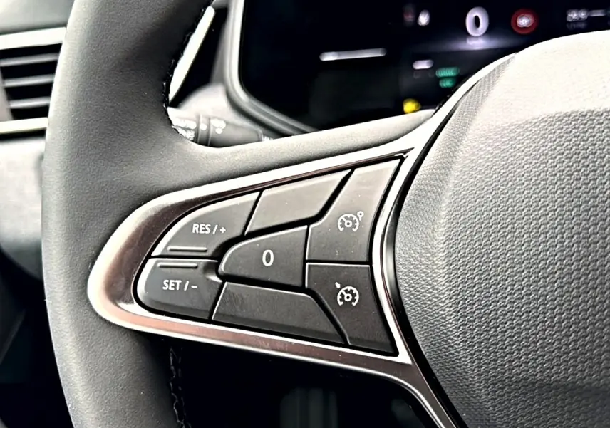 Gros plan sur les commandes du régulateur de vitesse au volant noir de la Renault Clio V 2026.