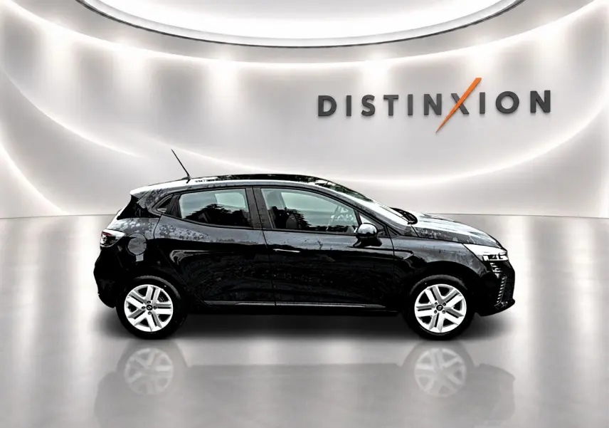 Profil droit de la Renault Clio V noire 1.0 TCe 90 Evolution dans un showroom lumineux avec logo Distinxion en arrière-plan.