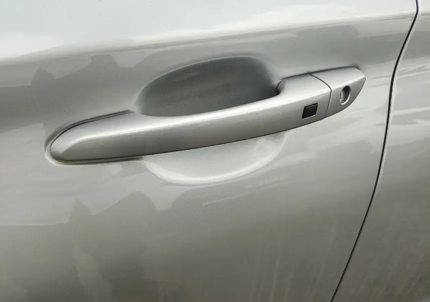 Poignée de porte côté gauche gris métallisé sur Hyundai Kona Electric 2025, avec bouton de déverrouillage.