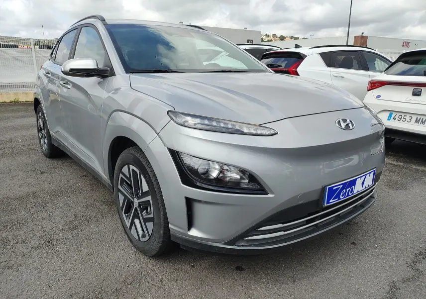 Vue 3/4 avant d'un Hyundai Kona Electric gris métallisé avec jantes alliage et calandre lisse sans grille.