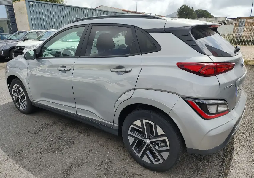 Vue 3/4 arrière côté droit d'un Hyundai Kona électrique gris métallisé avec jantes alliage et vitres surteintées.