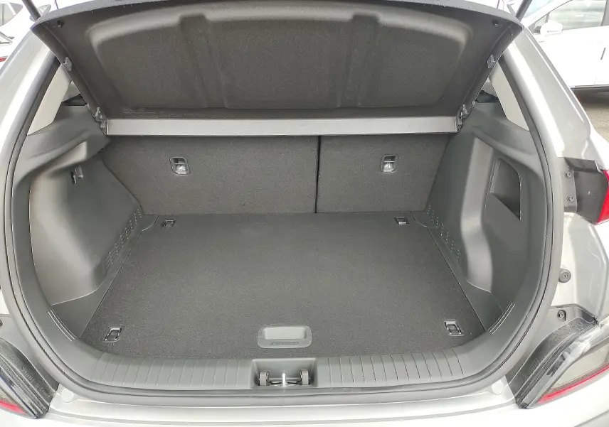 Coffre ouvert vu de l'arrière d'un Hyundai Kona électrique gris métallisé, montrant un espace de chargement propre et spacieux.