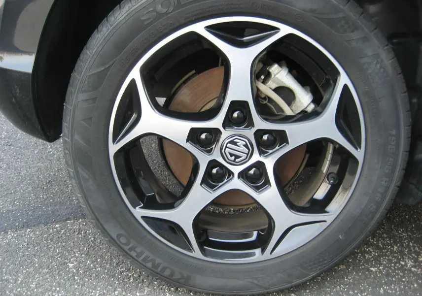 Gros plan sur la jante alliage noire et argentée du MG3 1.5 HYBRID+ 195 CH LUXURY noir, frein à disque visible.