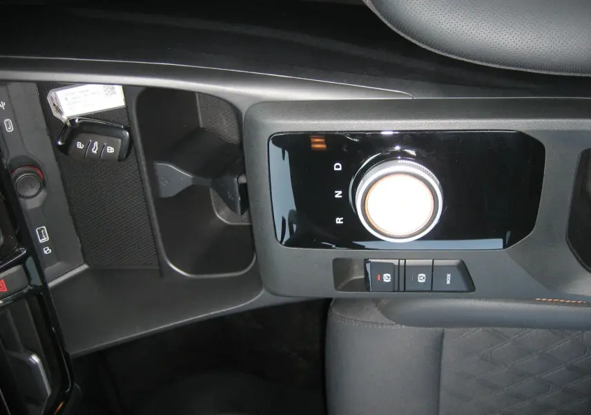 Vue rapprochée de la console centrale noire du MG3 1.5 HYBRID+ 2024, mettant en valeur la molette de boîte automatique et les boutons de frein à main.