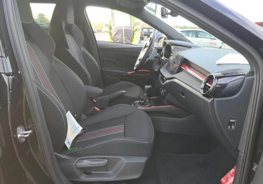 Vue intérieure côté gauche de la Skoda Fabia Monte Carlo 2024 avec sièges noirs à bandes rouges et tableau de bord moderne.