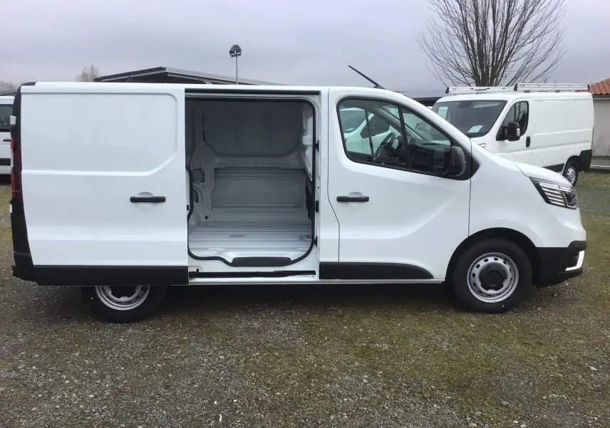 Renault Trafic Fourgon blanc vu de profil droit avec porte coulissante ouverte montrant l’espace de chargement vide.