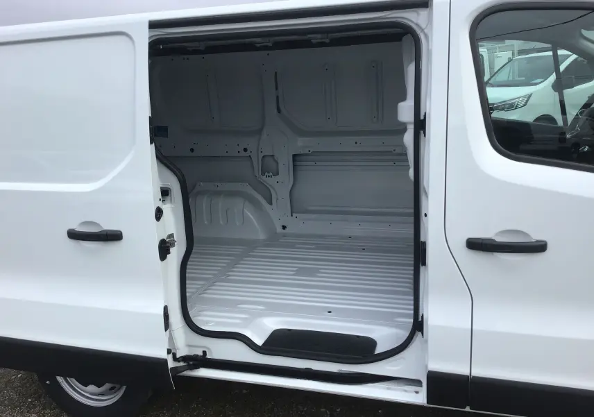 Vue latérale gauche d’un Renault Trafic Fourgon blanc 2025 avec porte coulissante ouverte montrant l’espace de chargement vide.