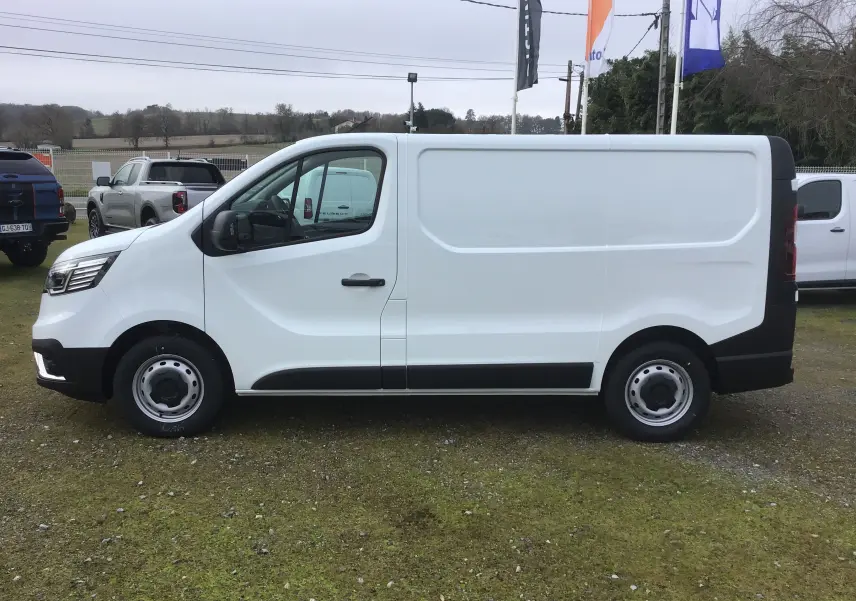 Renault Trafic Fourgon blanc vu de profil côté gauche, avec bandeau noir sur la partie basse et roues tôles.