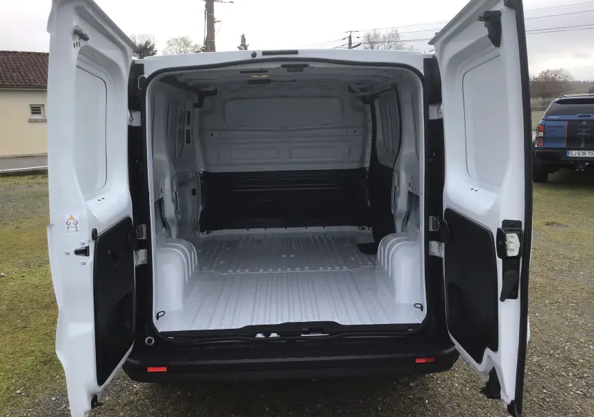 Vue arrière du Renault Trafic Fourgon blanc 2025 avec portes ouvertes montrant l’espace de chargement vide et spacieux.