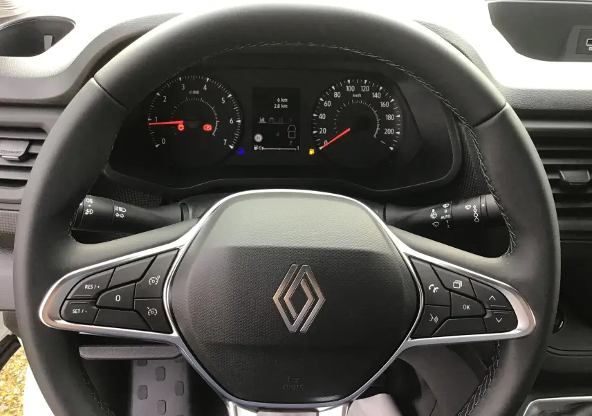 Vue rapprochée du volant noir du Renault Trafic Fourgon 2025 avec commandes intégrées et tableau de bord visible.
