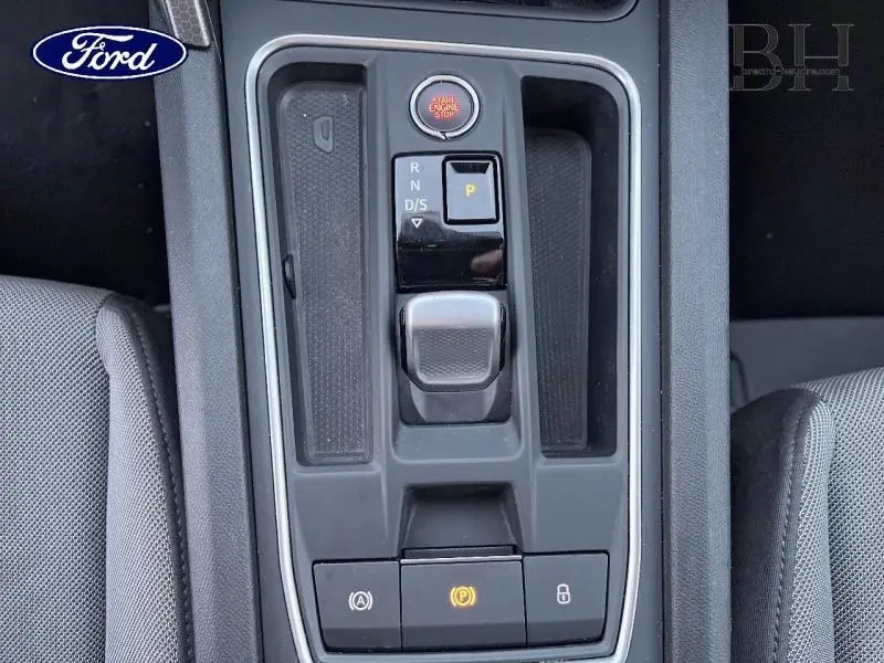Vue rapprochée de la console centrale grise de la SEAT LEON ST 1.0 eTSI 110ch Urban DSG7 avec levier de vitesses automatique.