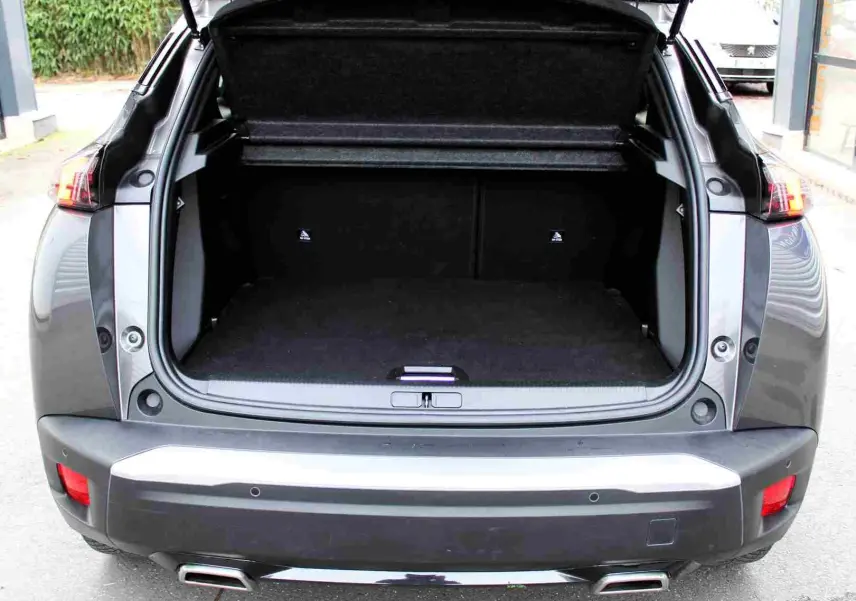 Vue arrière du Peugeot 2008 gris platinium de 2022 avec coffre ouvert et double sortie d'échappement visible.