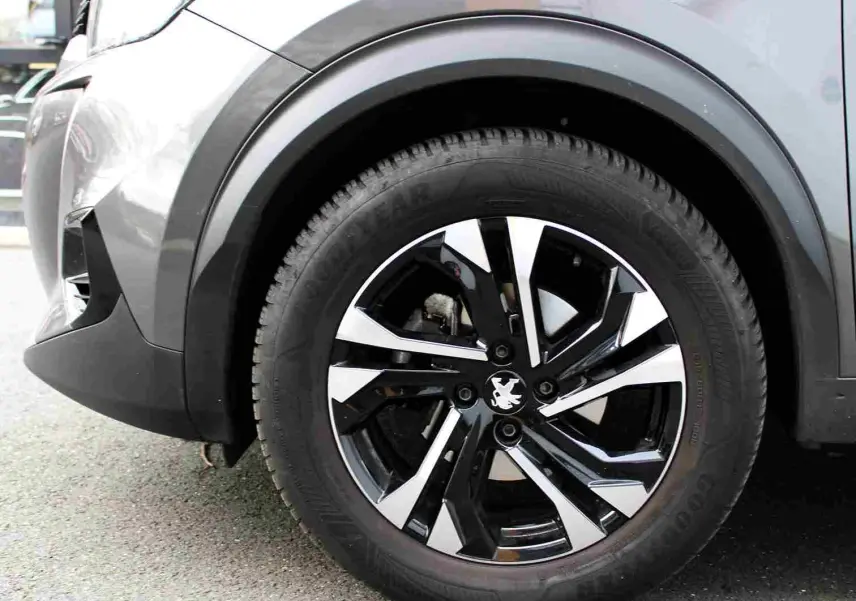 Gros plan sur la roue avant droite du Peugeot 2008 gris platinium, mettant en valeur la jante noire et argentée au design moderne.