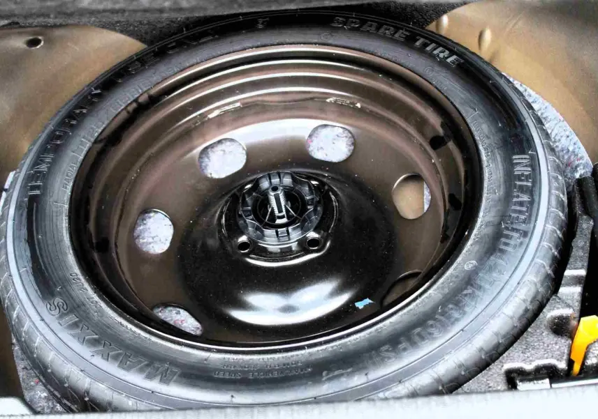 Gros plan sur la roue de secours noire du coffre du Peugeot 2008 gris platinium, mettant en valeur la jante acier simple.