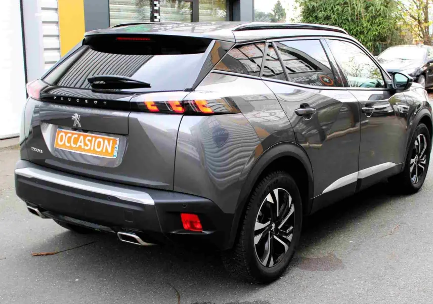 Vue 3/4 arrière droite d'un Peugeot 2008 gris platinium avec feux arrière LED et jantes alliage bicolores.