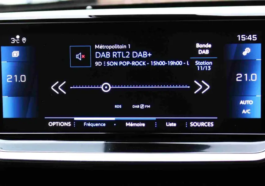 Écran tactile central du tableau de bord du Peugeot 2008 gris platinium affichant la radio DAB et la climatisation à 21°C.