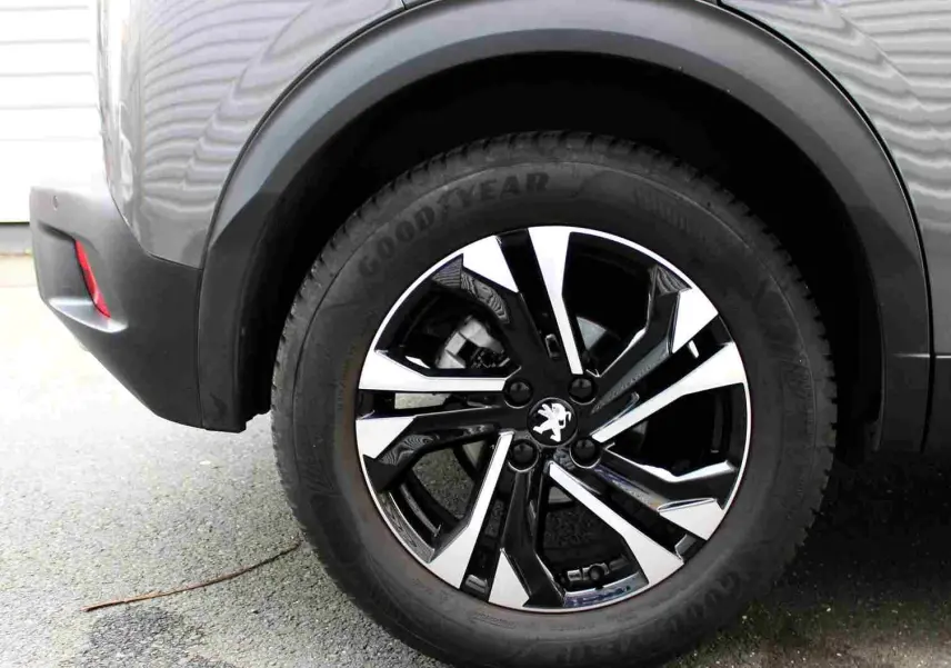 Gros plan sur la roue arrière droite d’un Peugeot 2008 gris platinium avec jante alliage bicolore et pneu Goodyear.