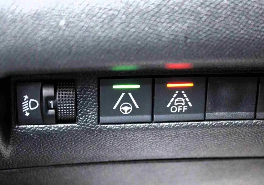 Gros plan sur les commandes d'assistance à la conduite avec voyants vert et rouge dans l'habitacle d'un Peugeot 2008 gris platinium.