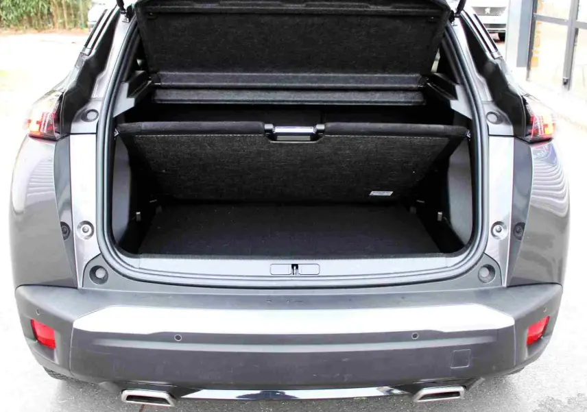 Vue arrière du coffre ouvert d'un Peugeot 2008 gris platinium 2022, soulignant l'espace de chargement et les feux arrière.