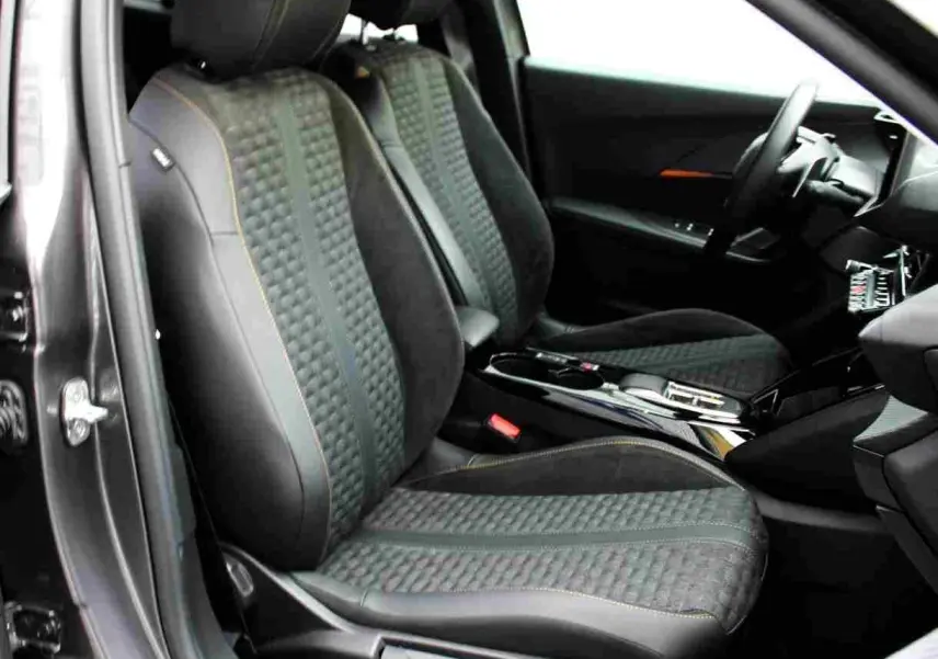 Intérieur avant droit du Peugeot 2008 gris platinium 2022, sièges en tissu et cuir avec surpiqûres orange visibles.