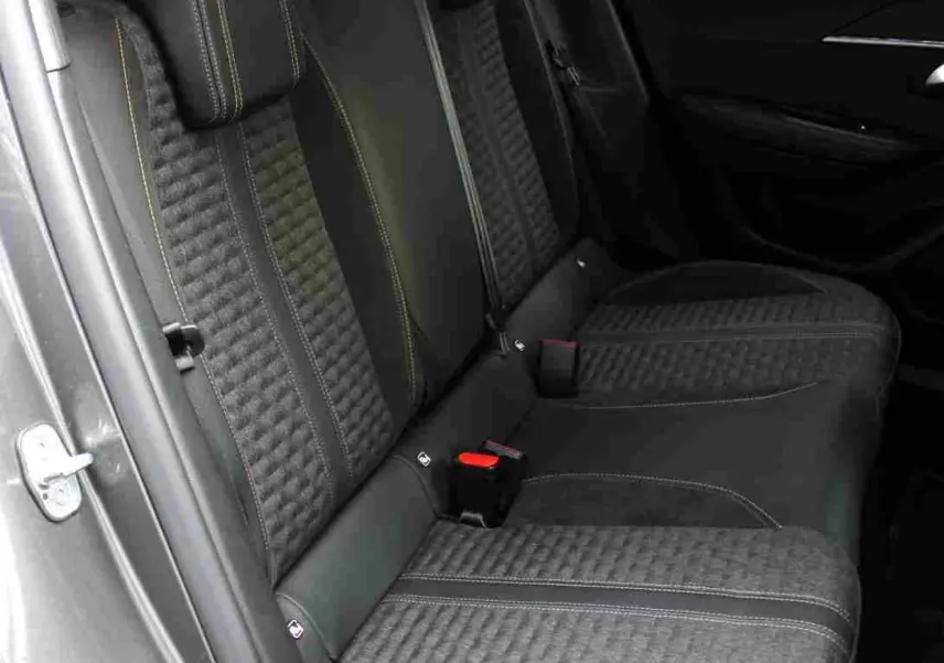 Vue intérieure côté gauche des sièges arrière en tissu et cuir noir avec surpiqûres jaunes du Peugeot 2008 gris platinium 2022.
